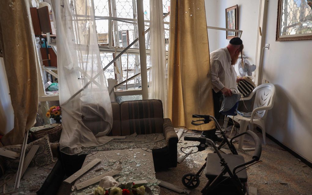 Een man neemt de schade op aan zijn huis in Haifa, nadat een raket uit Libanon het heeft getroffen. beeld AFP, Jack GUEZ