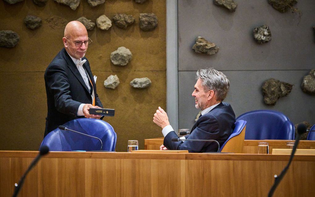 Een bode uit de Tweede Kamer overhandigt namens SGP-fractievoorzitter Chris Stoffer een Statenbijbel aan premier Dick Schoof. beeld Phil Nijhuis
