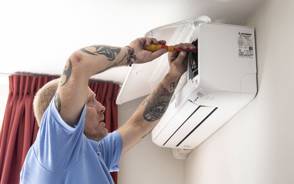 Een installateur plaatst een airco in een woning. In 2021 hing zo’n apparaat in een op de vijf Nederlandse woningen. beeld ANP, Pieter Stam de Jonge