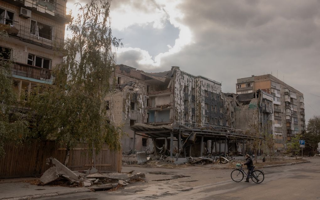 Een vrouw loopt met haar fiets langs beschadigde woongebouwen in Pokrovsk. beeld AFP, Roman Pilipey 