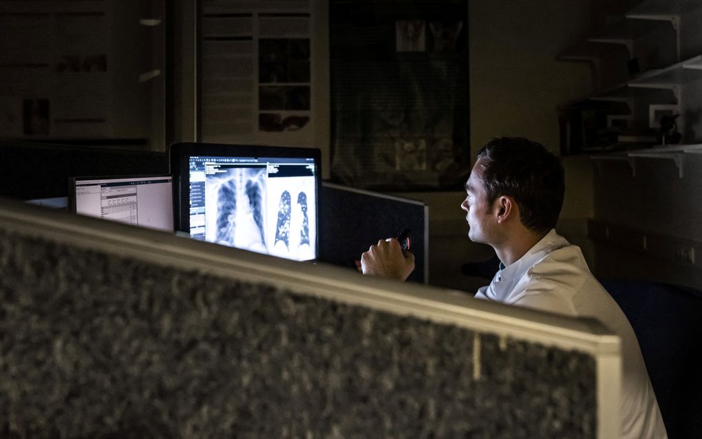 Een medewerker van de afdeling radiologie in het HMC Westeinde kijkt tijdens zijn nachtdienst naar de röntgenfoto's van een patient. Artsen moeten soms ’s nachts hun bed uit om een overledene te schouwen. beeld ANP, Remko de Waal