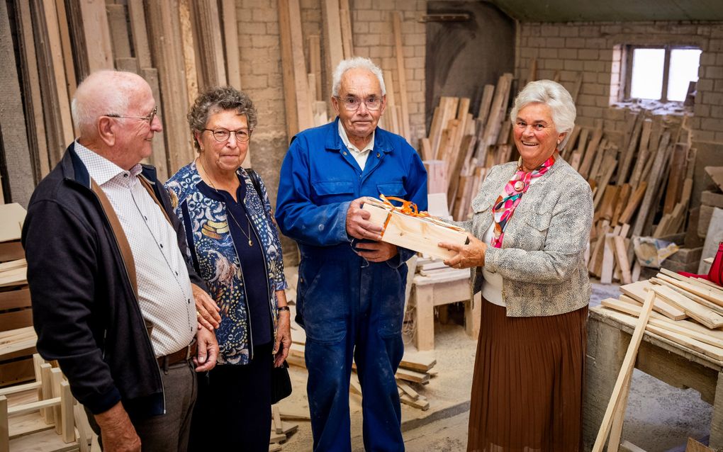 Vrijwilligers Silly den Breejen (r.) en Annie en Gerard IJskes (l.) van de Woord en Daadwinkel Zwanenburg overhandigen Koos Voets (m.) een notenpakket omdat zijn houtproducten al vijftien jaar een onmisbaar bestanddeel van de winkel vormen. beeld Cees van der Wal