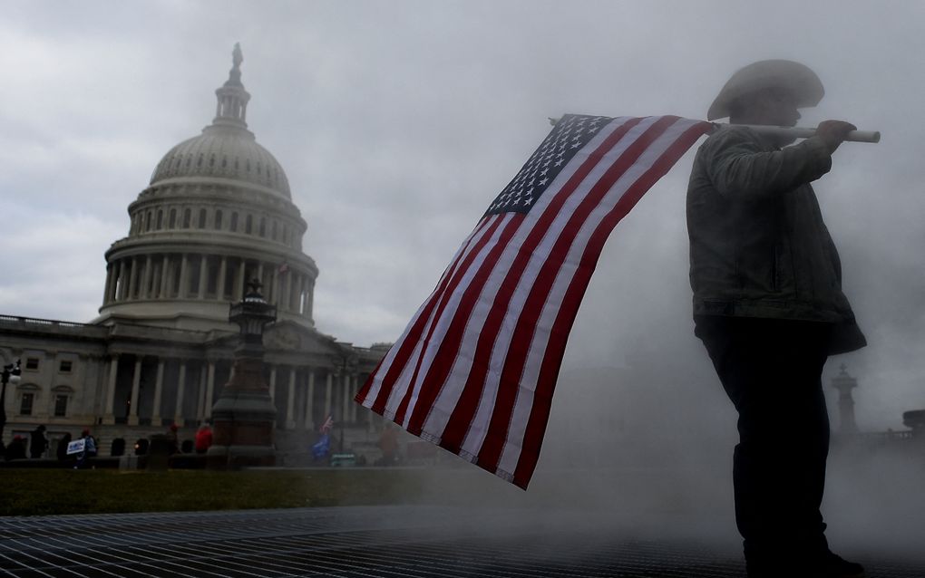 Een MAGA-Republikein zwaait op 6 januari 2021 bij de bestorming van het Capitool in de hoofdstad Washington D.C. met een Amerikaanse vlag. 
beeld AFP, Olivier Douliery