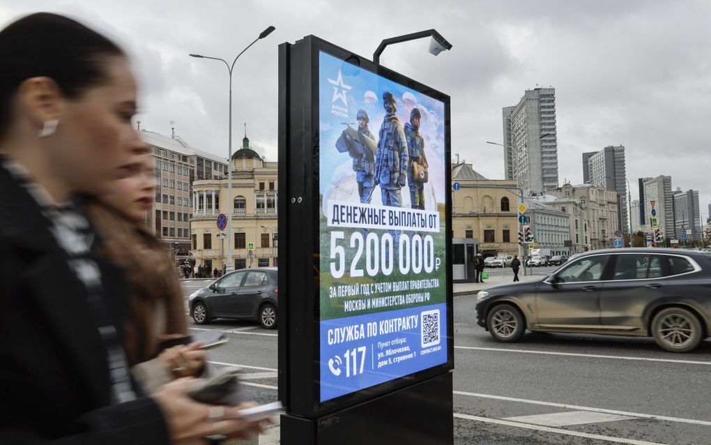 Twee Russische vrouwen lopen in hartje Moskou langs een reclamebord waarin mannen worden opgeroepen voor inzet op het slagveld in Oekraïne. beeld EPA, Yuri Kochetkov