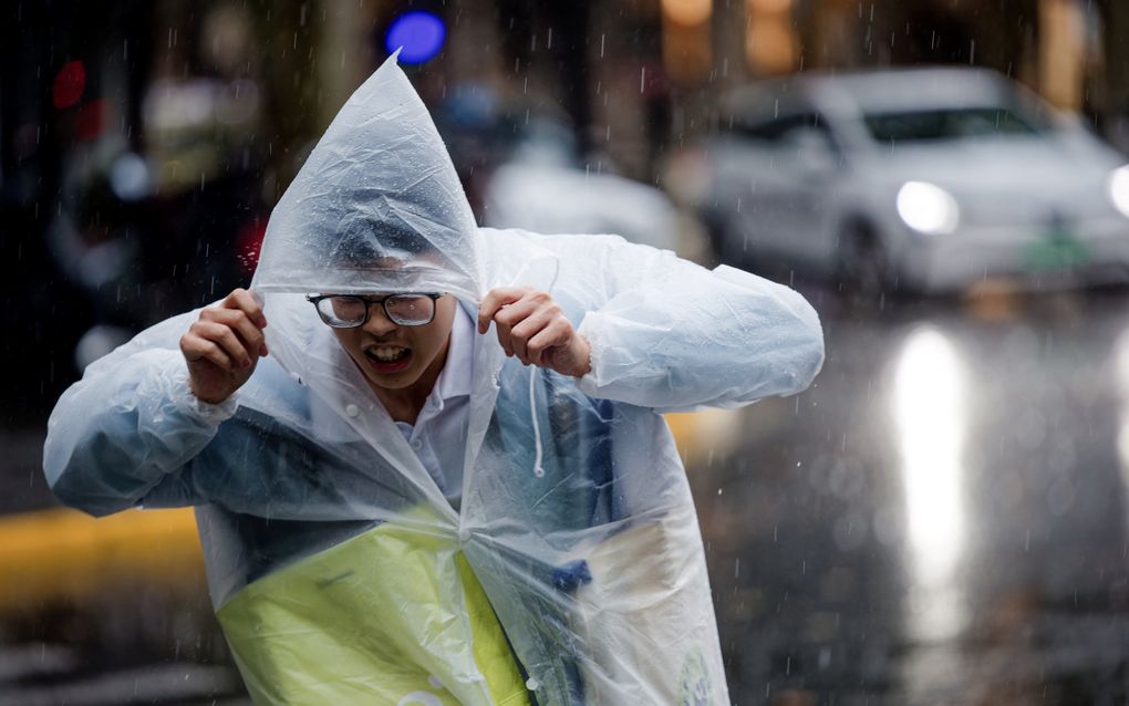 Een voetganger schuilt in zijn regenponcho. Typhoon Kong-rey in Shanghai (China) zorgt voor hevige regenval en storm. Delen van het openbaar vervoer werden stilgelegd en de overheid riep burgers op om voorraden in te slaan. Beeld EPA/ALEX PLAVEVSKI