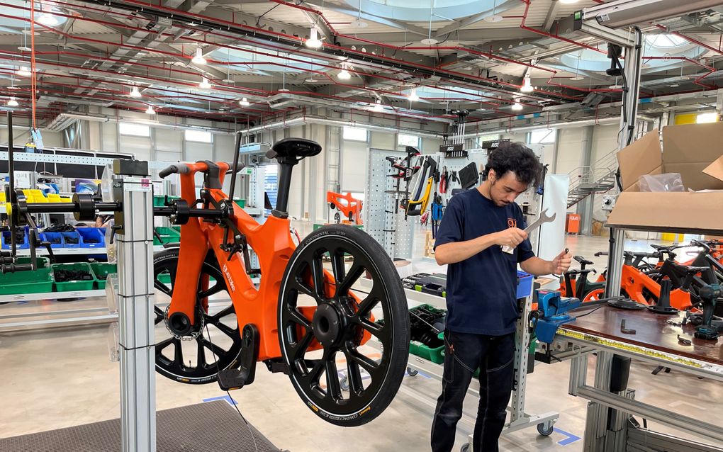 In een splinternieuwe fabriekshal sleutelt een werknemer een oranje RCYL-fiets in elkaar. beeld RD