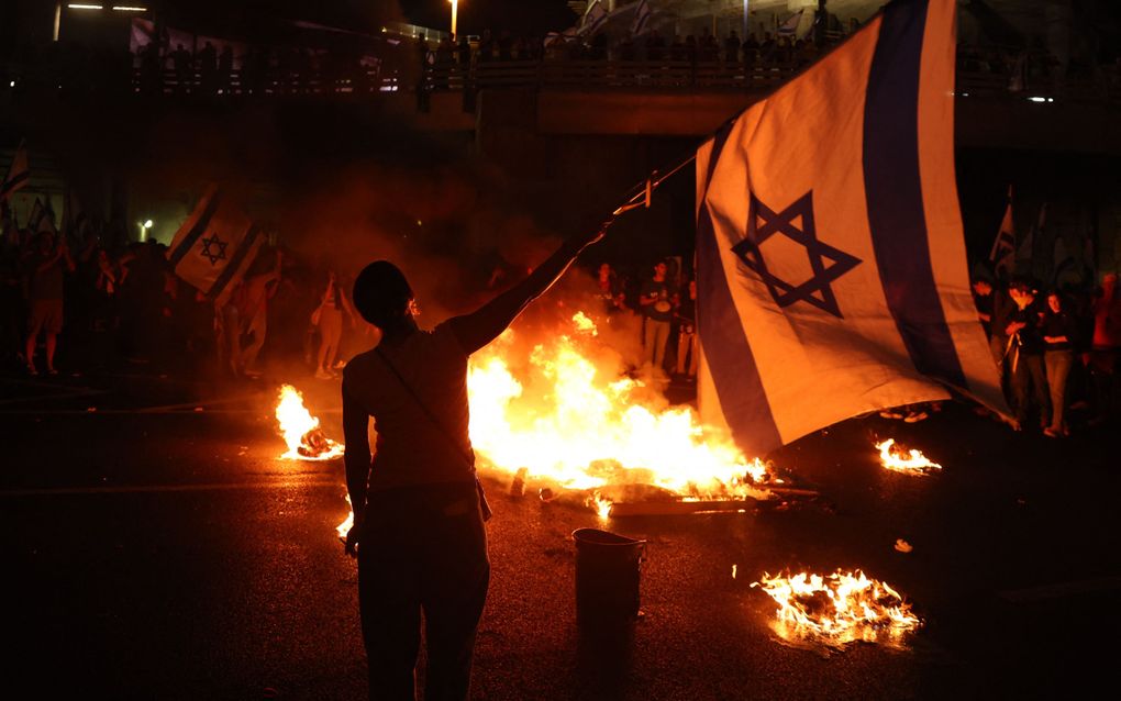 Israëlische demonstranten blokkeren een snelweg bij Tel Aviv, uit protest tegen het ontslag van defensieminister Yoav Gallant. beeld AFP, Jack Guez