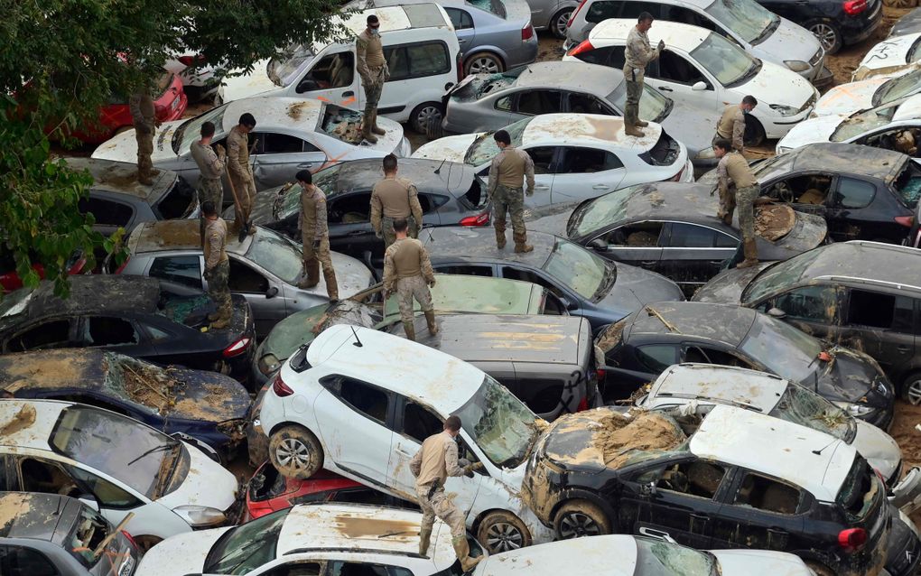 Militairen doorzoeken bemodderde auto’s van slachtoffers van de overstroming in het Spaanse Valencia. De overstroming kostte meer dan 210 mensen het leven en nog velen worden vermist. beeld AFP, Jose Jordan 