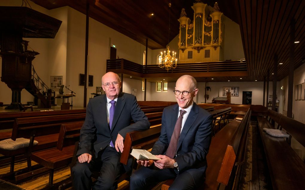 Dr. mr. K.W. de Jong (l.) en prof. dr. W.H.Th. Moehn in de Grote Kerk in Hilversum. Prof. Moehn houdt een facsimile-uitgave vast van Datheens Psalmberijming uit 1566 met daarin zijn vertaling van de Heidelbergse Catechismus, liturgische formulieren en gebeden. beeld Ruben Schipper