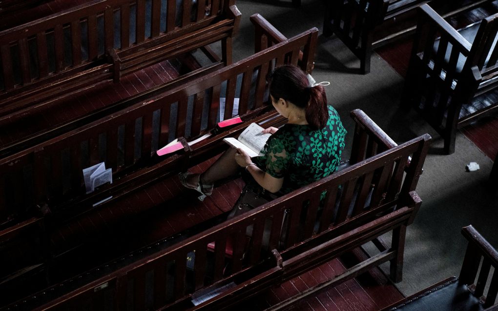 Een vrouw leest een Bijbel in een kerk in Wuhan. beeld AFP, Nicolas Asfouri