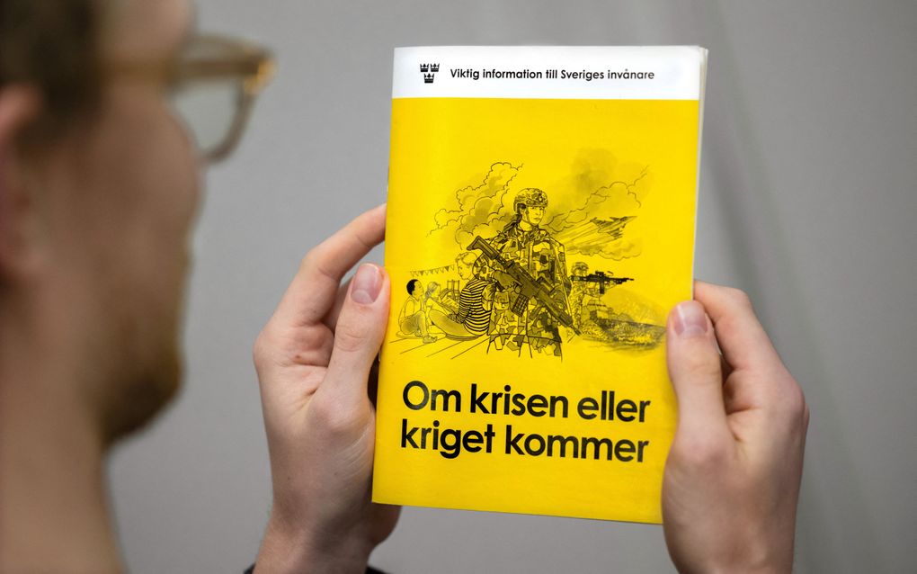 Een man houdt de nieuwe versie van de brochure ”Als de crisis of oorlog komt” vast. beeld AFP, Claudio Bresciani 