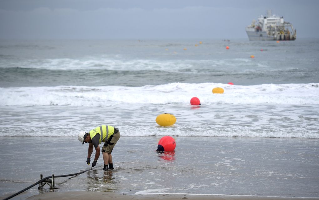 Een operator werkt tijdens het vastleggen van een onderzeese glasvezelkabel op het strand van Arrietara bij het Spaanse Sopelana. beeld AFP, Ander Gillenea 