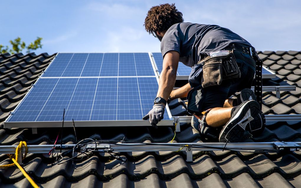 Een installateur plaatst zonnepanelen op het dak van een woonhuis. Zonder salderingsregeling blijven zonnepanelen rendabel als het eigen verbruik wordt opgeplust.  beeld ANP, Remko de Waal