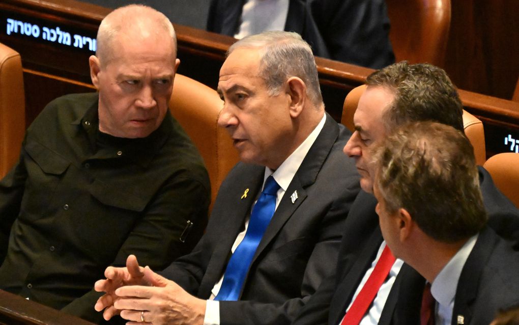 Oud-minister Yoav Gallant (links) van Defensie praat in het Israëlische parlement met Benjamin Netanyahu (in het midden). beeld EPA, Debbie Hill