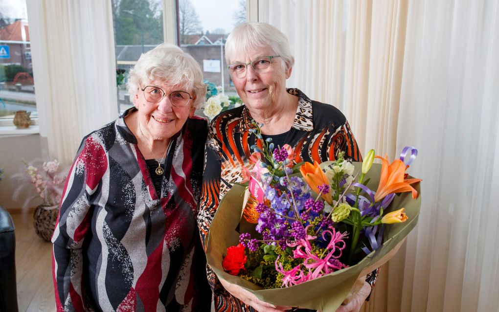 Tiny Catsburg-Bruins (l.) geeft bloemen aan haar vriendin en mantelzorger Yvonne van Kooten-Heijkamp. „Ik hoef maar een kik te geven en ze is er al.”