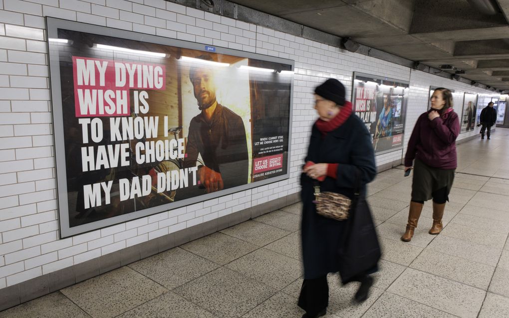 Voetgangers lopen op het metrostation Westminster in Londen langs posters die de ”assisted dying bill” promoten. beeld EPA, Tolga Akmen