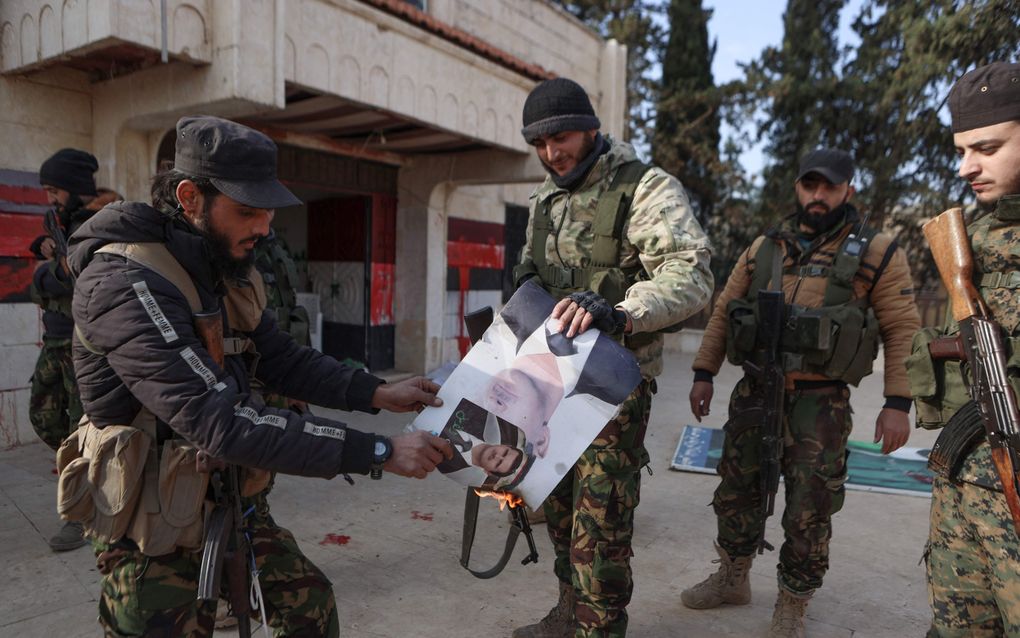 Door Turkije gesteunde strijders van Hayat Tahrir al-Sham (HTS) steken een afbeelding van de Syrische president Bashar al-Assad vrijdag in brand in Zarbah. De rebellen voeren een offensief in het noorden van de Syrische provincie Aleppo tegen de regeringstroepen. beeld AFP, Aaref Watad