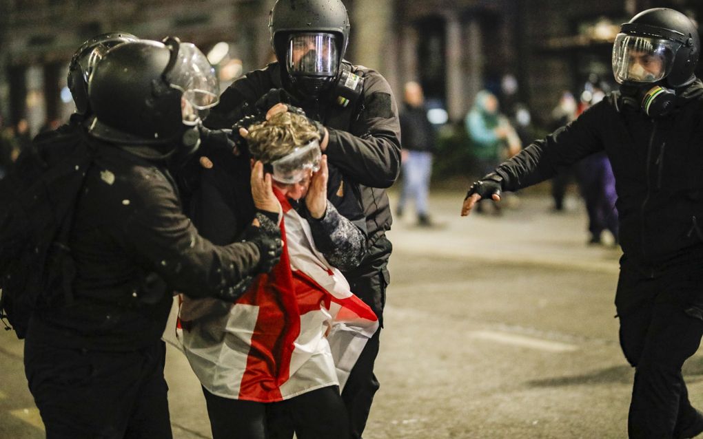 Politieagenten houden een demonstrant aan tijdens een betoging voor het parlementsgebouw in Tbilisi. beeld EPA, David Mdzinarishvili 