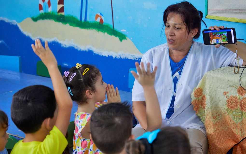 Een medewerkster van de kerkelijke kinderopvang in Sancti Spiritus (Cuba) vertelt kinderen een Bijbelverhaal. Bij gebrek aan papieren kinderbijbels gebeurt dat met digitale middelen. beeld Jaco Klamer