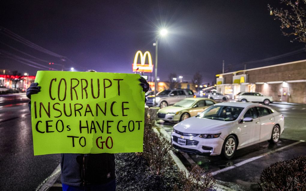 Een vrouw houdt een protestbord vast buiten het McDonald's-filiaal in Altoona waar de politie Luigi Mangione heeft opgepakt. beeld EPA, Kameron Croston