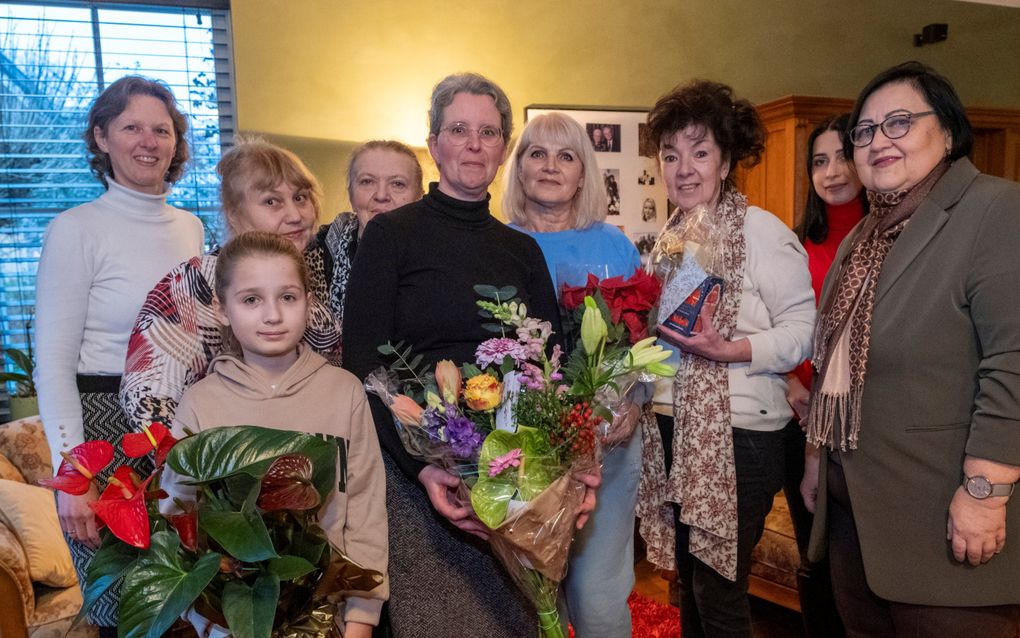 Annelies Kraamer (uiterst links) geeft samen met zeven Oekraïners Elna Moerdijk (m.) een bos bloemen. „Ze laat ons thuisvoelen in Nederland.’’ Nieuwdorp   beeld Dirk-Jan Gjeltema