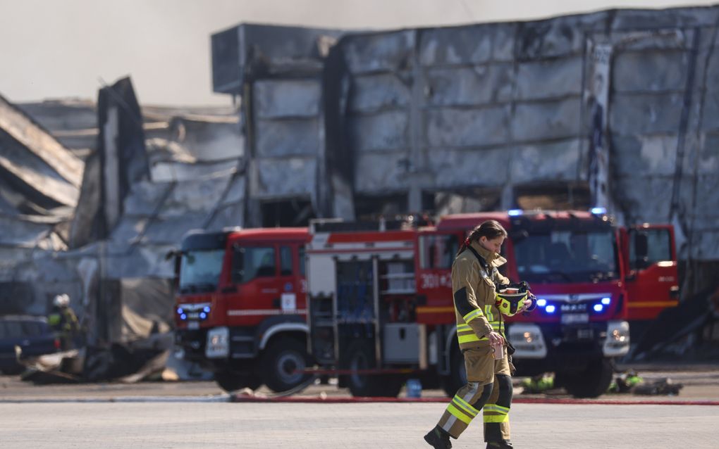 Een brandweervrouw voor het door brand vernietigde winkelcentrum in het Poolse Warschau, in mei van dit jaar. beeld EPA, Leszek Szymanski