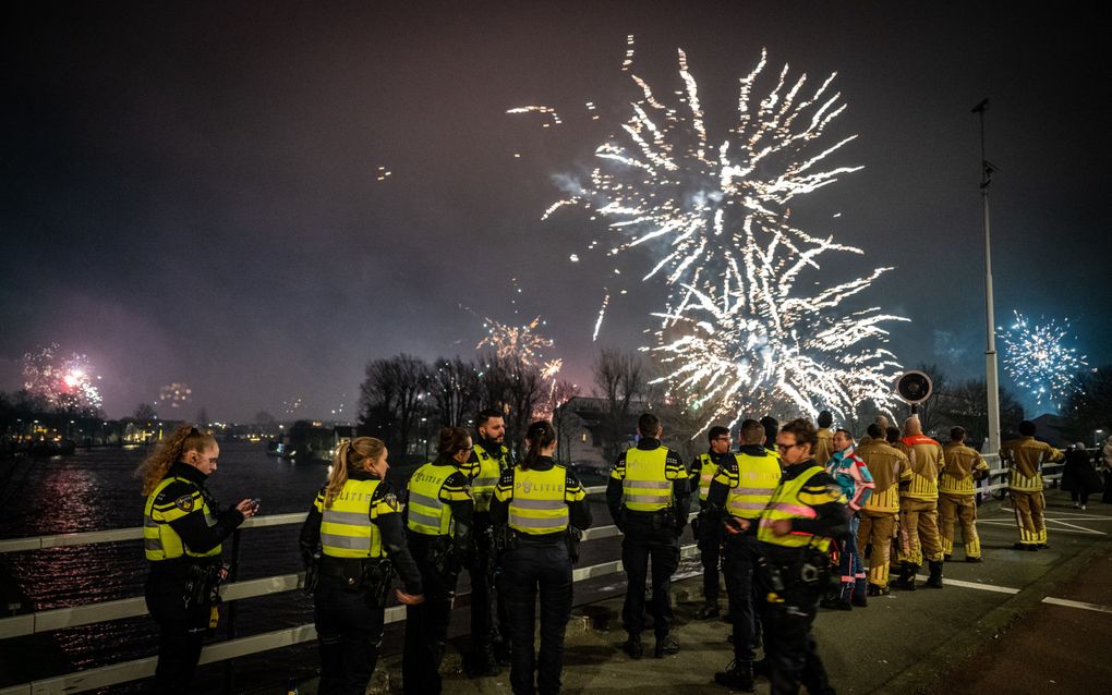 Agenten en hulpverleners kijken  op een brug in Alphen aan den Rijn naar vuurwerk tijdens de jaarwisseling. Enkele auto’s gingen in vlammen op. beeld ANP, Josh Walet