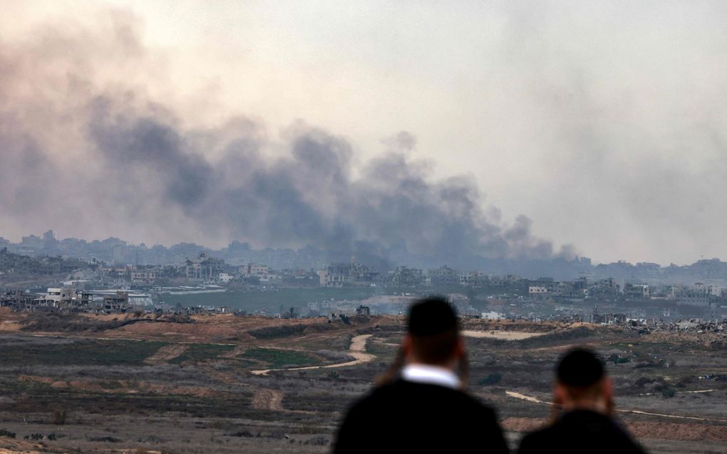 Joodse mannen kijken vanaf de grens naar de bombardementen van het Israëlische leger op Gaza. beeld AFP