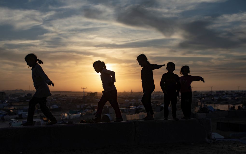 Palestijnse kinderen lopen over een muur dichtbij het Khan Younis tentenkamp in het zuidelijke deel van de Gazastrook. beeld EPA, Haitham Imad 