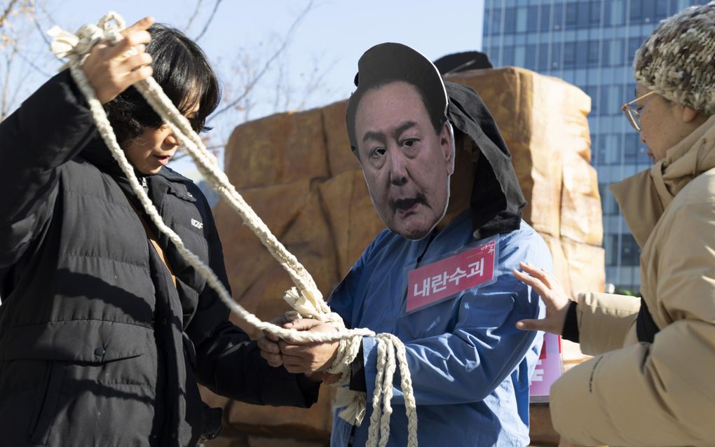 Activisten dragen een papieren masker van de Zuid-Koreaanse president Yoon Suk-yeol tijdens een demonstratie in Seoul op 19 december. Zij riepen al veel langer om de arrestatie van Yoon. beeld EPA, Jeon Heon-Kyun 