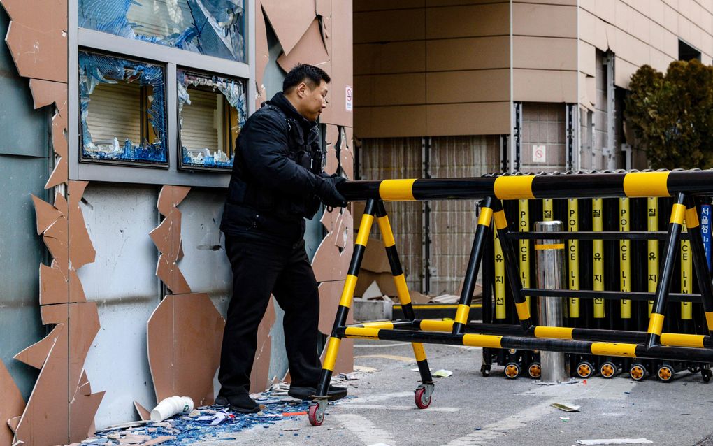 Een politieagent duwt een mobiele barrière naast kapotte ramen buiten de rechtbank. beeld AFP, Anthony Wallace