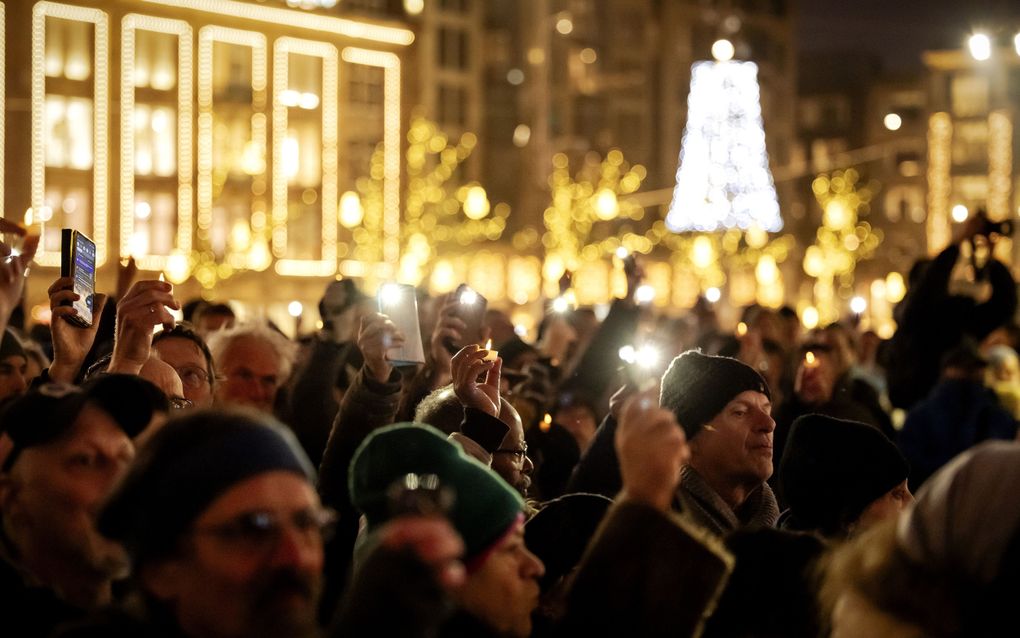 Belangstellenden houden lichtjes omhoog tijdens de viering van het Joodse Chanoekafeest op de Dam in december 2024. beeld ANP, Robin van Lonkhuijsen