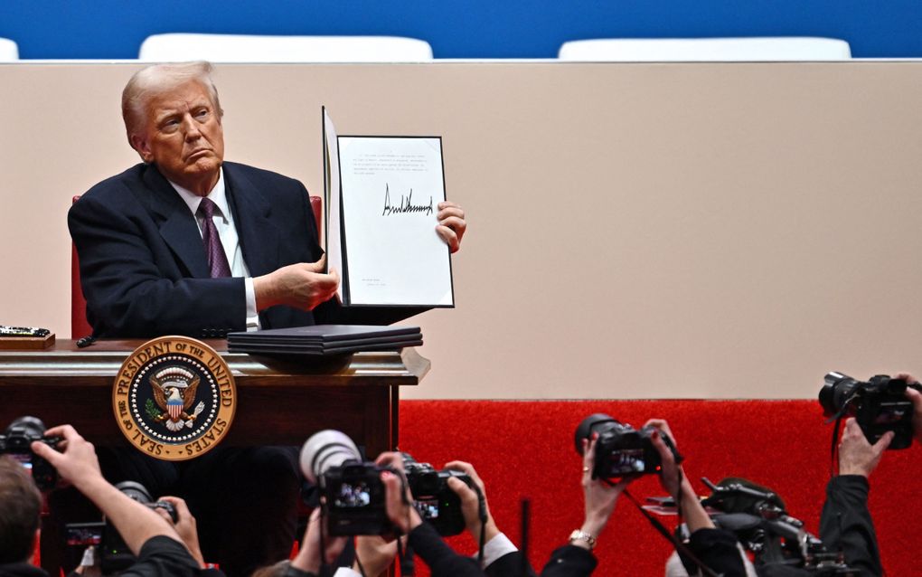 President Donald Trump houdt maandag decreten vast die hij zojuist heeft getekend in de Capital One Arena in Washington D.C. beeld AFP, Angela Weiss