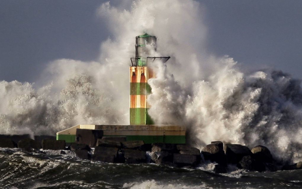 De groene vuurtoren op de Zuidpier bij IJmuiden heeft het flink te verduren. Het Noordzeewater wordt door een storm hoog opgezweept. beeld ANP, Olaf Kraak 