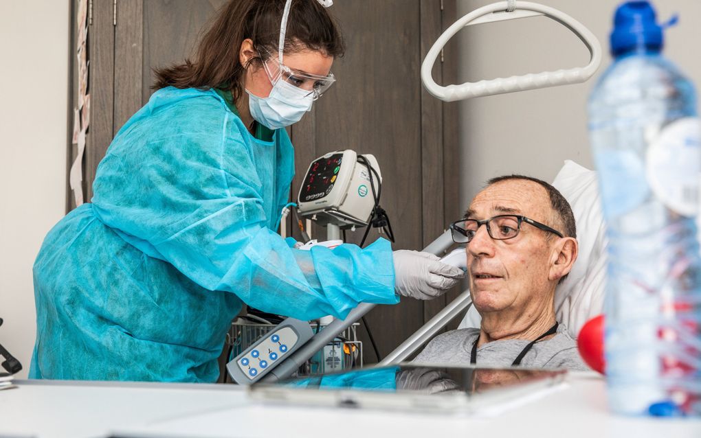 Uit vrees om een tuchtklacht aan de broek te krijgen, zetten veel artsen een tandje bij. Foto: een zorgmedewerker verzorgt een coronapatiënt in woonzorgcentrum Nieuw Rijsenburgh in Sommelsdijk. beeld ANP, Jeffrey Groeneweg