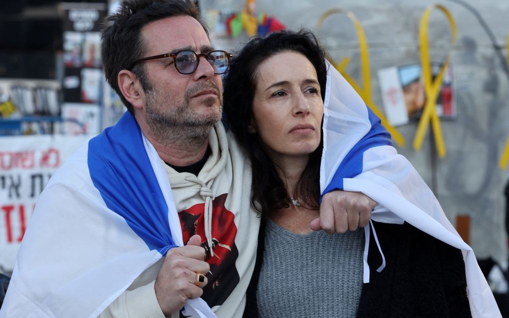 Een man en vrouw volgen zaterdag de gevangenruil via een groot scherm op een plein in Tel Aviv. beeld AFP, Jack Guez