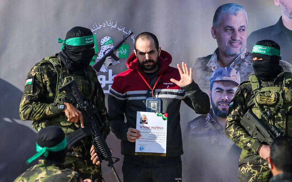 Gwapende Hamasterroristen escorteren Yarden Bibas naar een voertuig van het Rode Kruis. beeld AFP, Eyad Baba