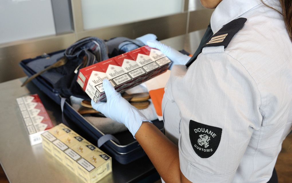 Een medewerker van de douane in Rotterdam controleert een koffer op sigarettensmokkel. beeld ANP, Lex van Lieshout