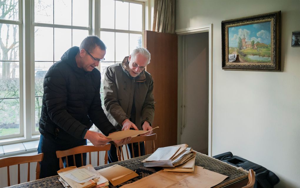 Ds. B. van der Linden (r.) en ouderling-kerkrentmeester H. Colijn met enkele archiefstukken, waaronder bouwtekeningen van de kerk. beeld Maikel Samuels