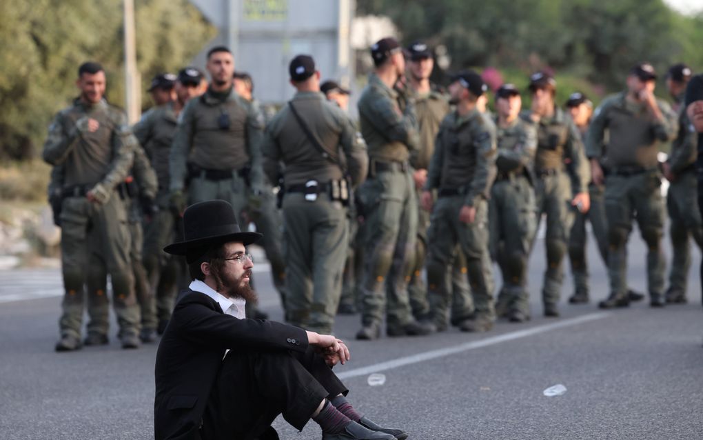 Een ultraorthodoxe man zit op de weg in Bnei Brak tijdens een protest tegen de dienstplicht voor religieuze Joden. beeld EPA, Abir Sultan