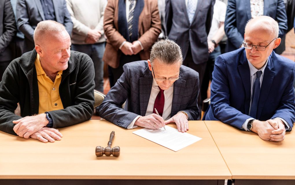 Ds. H.Sj. Wiersma zet zaterdag zijn handtekening onder het fusiedocument van DGK en de GKN, in de Bethelkerk in Harderwijk. Rechts naast hem ds. A. Bas. beeld André Dorst 