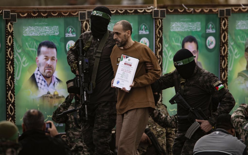 Hamasterroristen begeleiden de Israëlische gijzelaar Eli Sharabi naar een podium in de Gazastrook. beeld EPA, Jaitham Imad