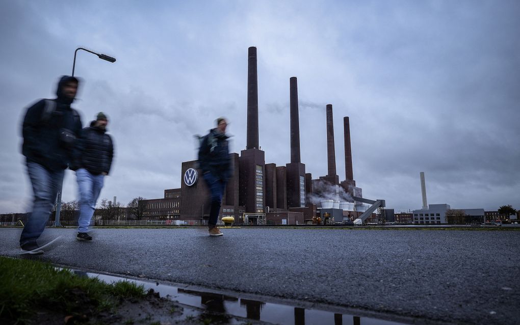 Drie mannen lopen langs de Volkswagenfabriek in de Duitse stad Wolfsburg. De Europese economie blijft achter door onder meer een wirwar aan regeltjes. In het nieuwe werkprogramma van de Europese Commissie zitten diverse voorstellen om de concurrentiekracht te verstevigen. beeld AFP, Ronny Hartmann