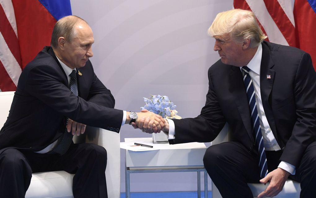 De Russische president Vladimir Poetin en de Amerikaanse president Donald Trump geven elkaar in 2017 tijdens de G20-top in Hamburg een hand. beeld AFP, Saul Loeb