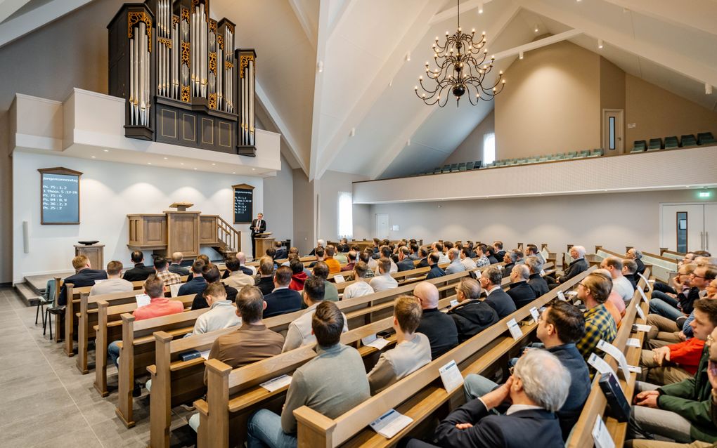 Ds. R. van de Kamp (achter de katheder) was zaterdag een van de sprekers op de jongemannendag van de Hersteld Hervormde Kerk. beeld Hanno de Vries