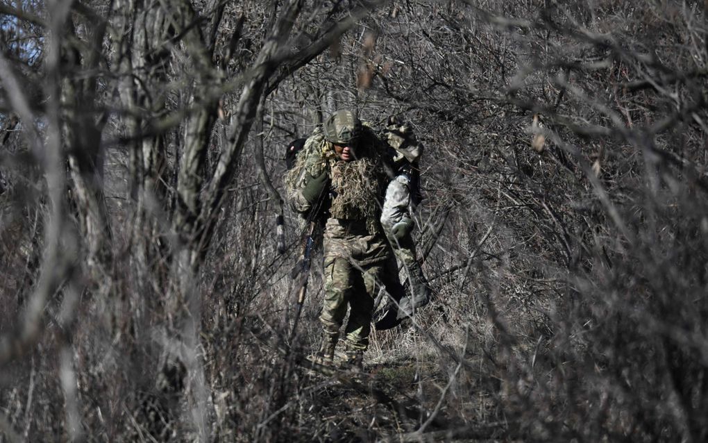 Een Oekraïense soldaat draagt tijdens een militaire oefening een andere militair op zijn schouders. beeld AFP, Genya Savilov