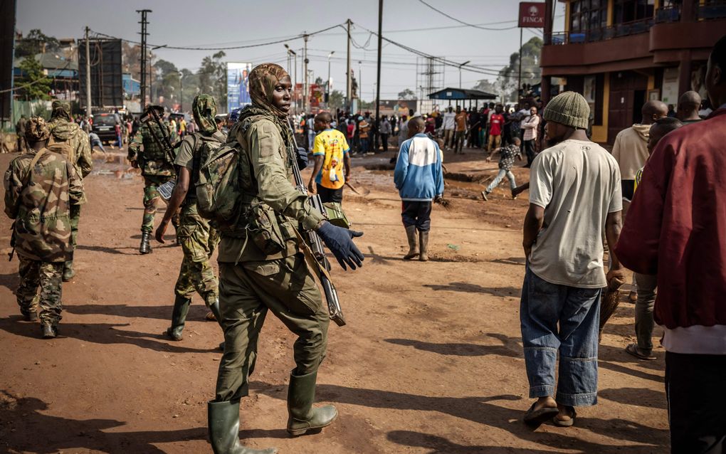 Een M23-rebel maant de lokale bevolking van Bukavu afstand te houden van de militairen. beeld AFP, Luis Tato