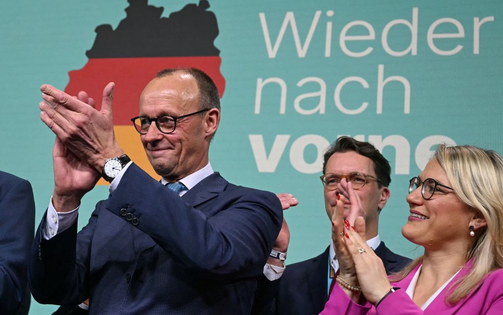 CDU-leider Friedrich Merz applaudisseert voor zijn aanhangers na de bekendmaking van de eerste verkiezingsuitslag van de Duitse parlementsverkiezingen. beeld AFP, Ina Fassbender 