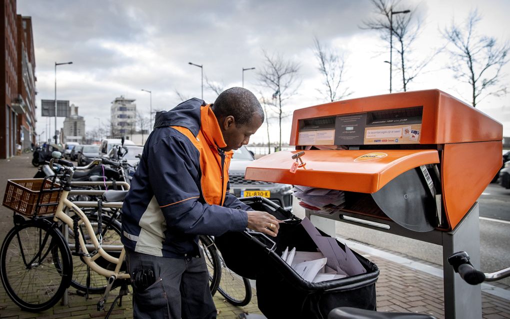 Een medewerker van PostNL leegt in Amsterdam een brievenbus. Eerder dit jaar kondigde de onderneming aan de meeste brievenbussen eerder op de dag te gaan legen, in plaats van na 17.00 uur. beeld ANP, Koen van Weel