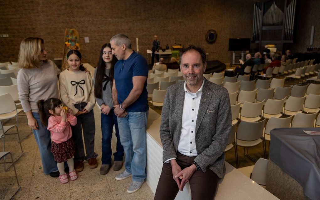 Ds. Lex Boot en het Oezbeekse gezin Babayants –een zoon ontbreekt op de foto– in de kerkzaal van de Open Hof in Kampen, waar een voortdurende kerkdienst plaatsheeft. beeld Freddy Schinkel